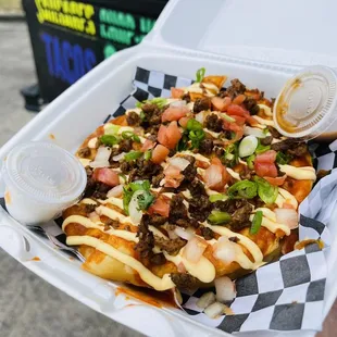 a hand holding a container of nachos