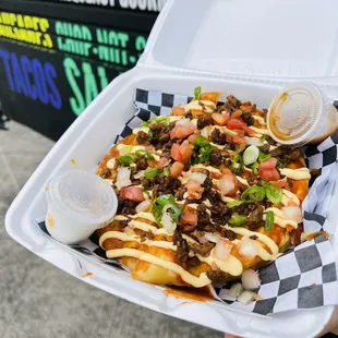 a person holding a tray of nachos