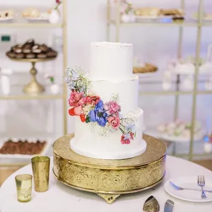 a white wedding cake on a gold stand