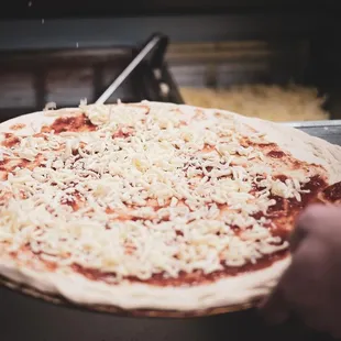 a person placing cheese on a pizza