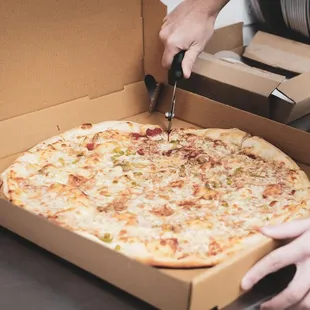 a person cutting a pizza in a box
