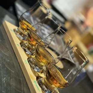 four glasses of whiskey on a wooden tray