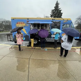 a group of people standing in front of a food truck