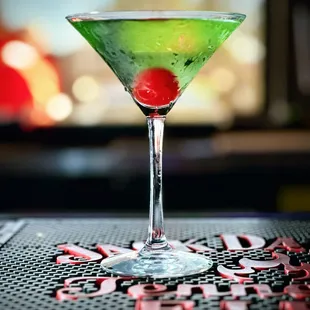 a green martini with a red cherry