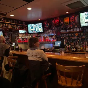 people sitting at the bar watching televisions
