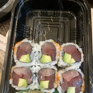 a tray of sushi with avocado