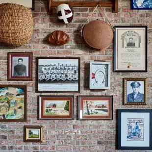 a brick wall with a variety of framed pictures