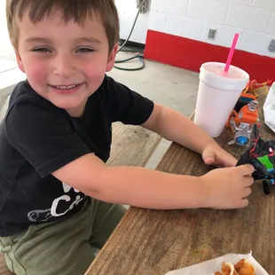a young boy sitting at a table with food