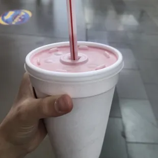 a hand holding a cup with a straw