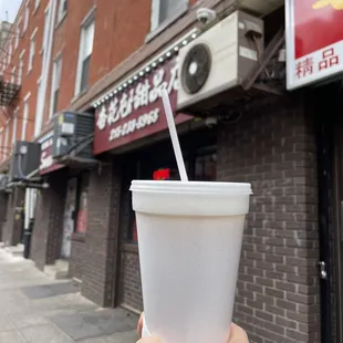 a hand holding a cup with a straw