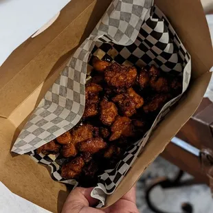 a person holding a bag of fried chicken