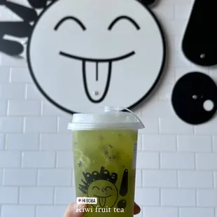a hand holding a cup of green tea