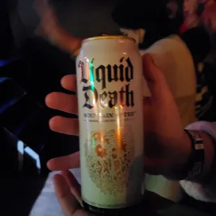 a hand holding a can of liquid death