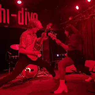 a man and a woman playing guitar on stage