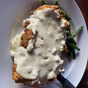 a plate of food with gravy and green beans