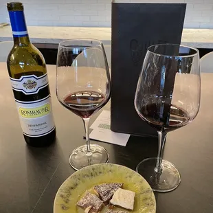 a plate of food and two wine glasses