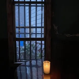 a candle on a table in front of a window