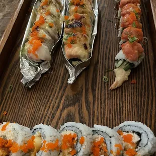 a variety of sushi rolls on a wooden tray