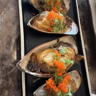 three oysters on a black plate