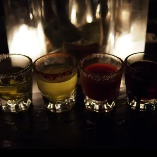 a row of shot glasses in front of a lit candle
