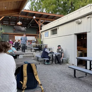 More outdoor patio with covered seating wraps around the back and a TV