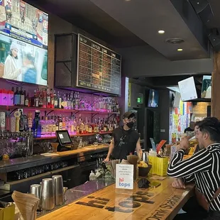 people sitting at a bar watching televisions