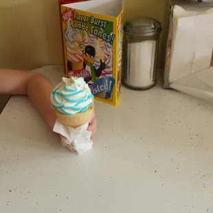 a little girl sitting at a table with a cupcake