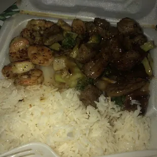 a takeout container with rice, meat, and broccoli