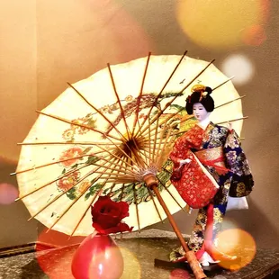 a geisha doll holding an umbrella