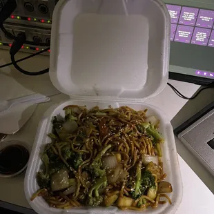 a take out container with noodles and broccoli