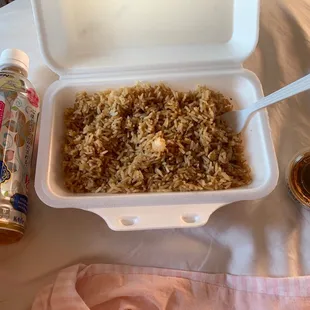 a container of rice with a spoon and a container of sauce