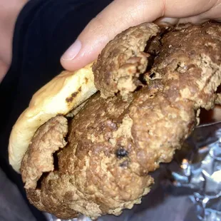 a hand holding a fried chicken sandwich