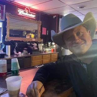 a man in a cowboy hat sitting at a bar