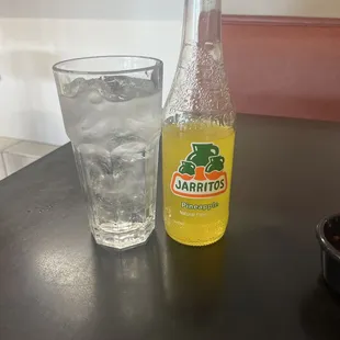 a glass of water and a bottle of jarrito
