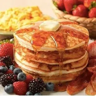 a stack of pancakes with syrup and fruit