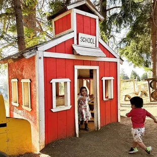 two children playing in a red playhouse house