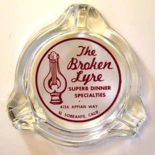 a glass ashtray with the logo of the broken lyre