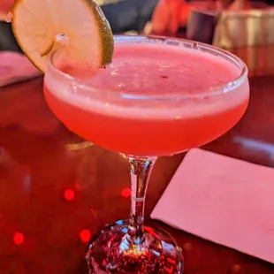 a pink cocktail with a slice of lime