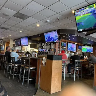 people sitting at the bar watching tvs