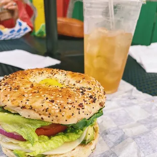 a bagel sandwich with lettuce, tomato, onion, and pickles