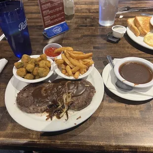 Hamburger steak with onions and gravy with sides of okra and fries.