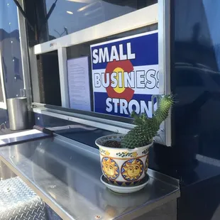 a small potted cactus in front of a small business sign