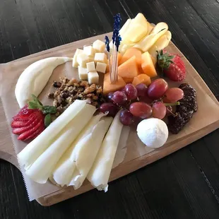 a variety of cheese and fruit on a cutting board