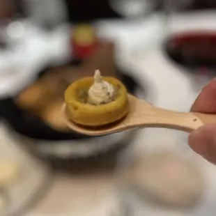 a hand holding a wooden spoon with a piece of food on it