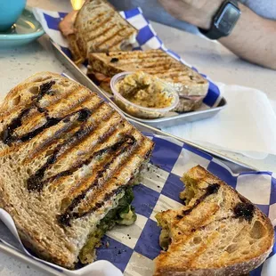 Pesto caprese sandwich in foreground, ham havarti sandwich in background with mustard on the side