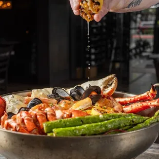 a person sprinkling salt onto a bowl of seafood