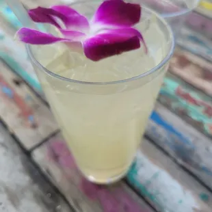 a glass of lemonade with a purple flower