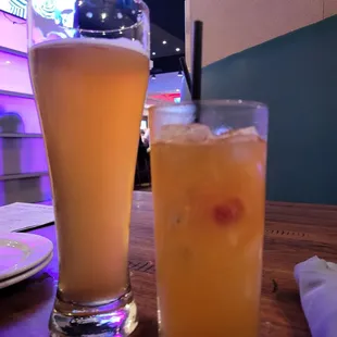 a glass of orange juice next to a tall glass of orange juice