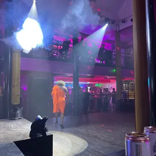 a man in an orange outfit on stage