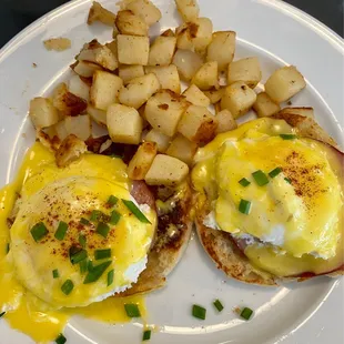 two eggs benedicts and potatoes on a plate